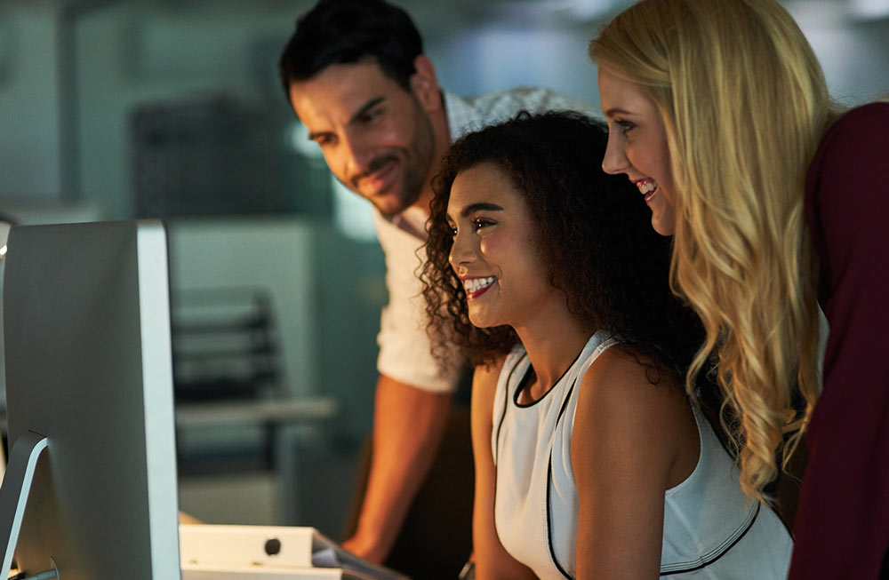 Three AI Aptitude smart employees working on a computer.